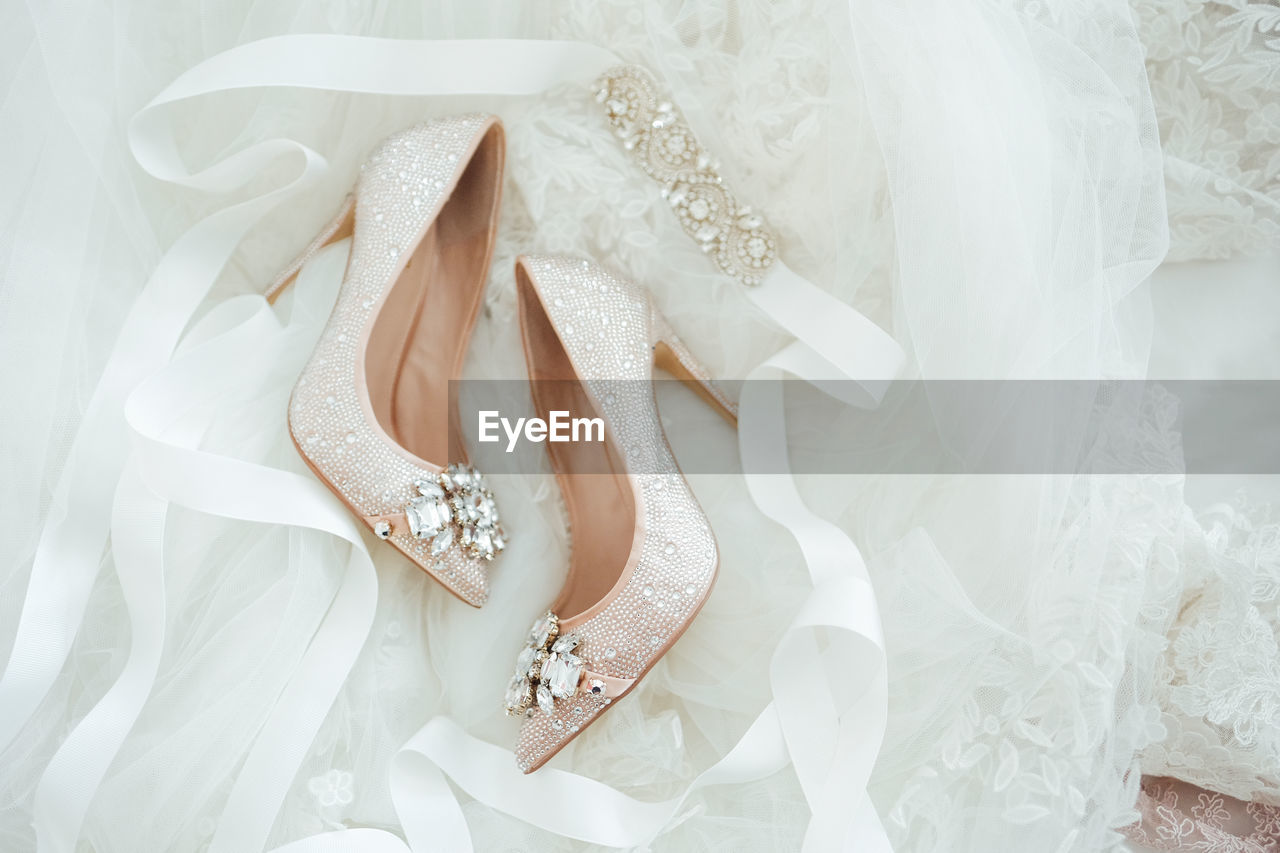 Close-up of wedding shoes dainty beautiful flatlay details stillettos lace background crystals