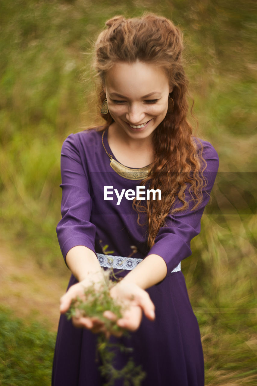 Young woman smiling while standing on field