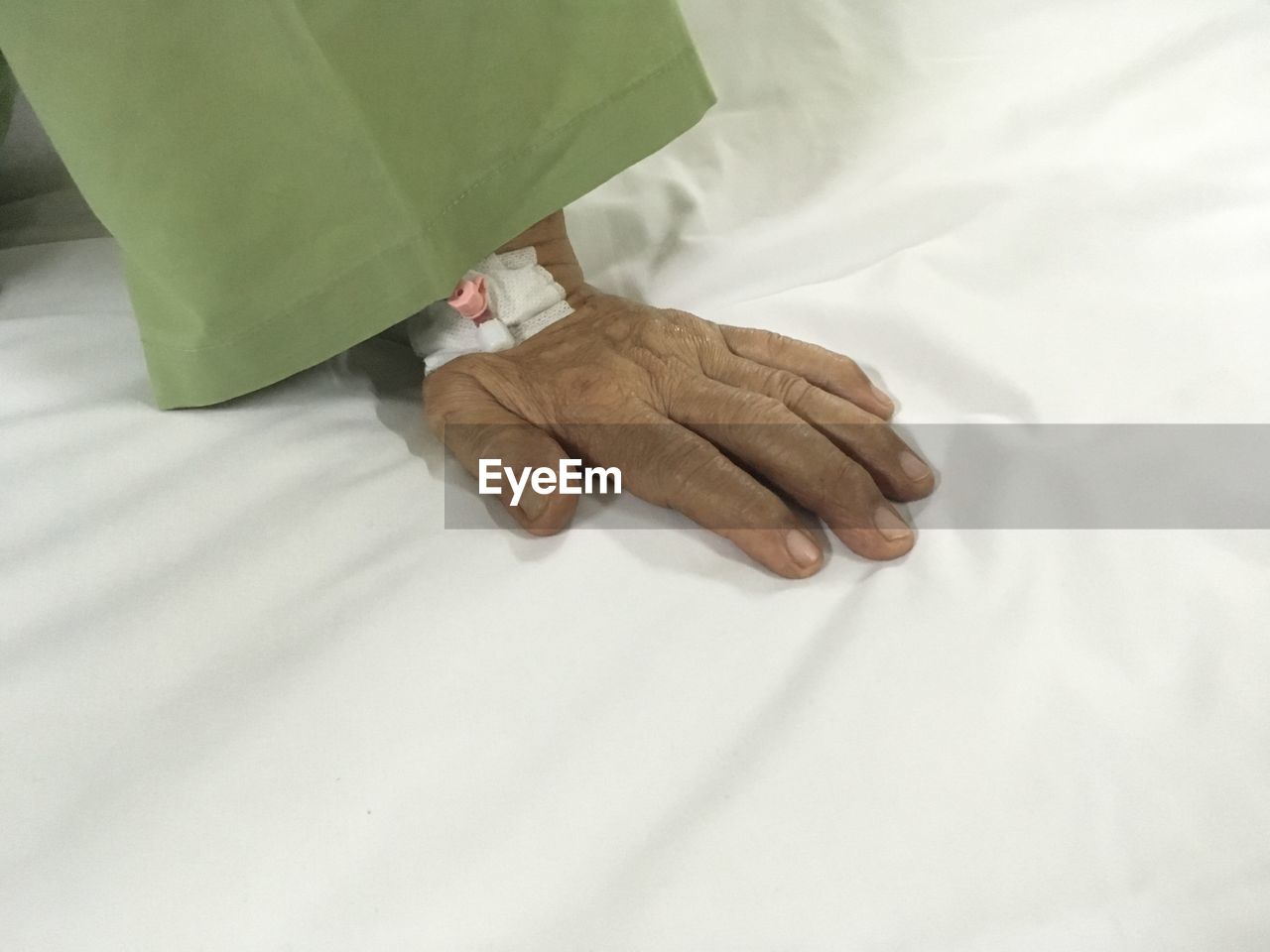 Cropped hand of patient on bed in hospital