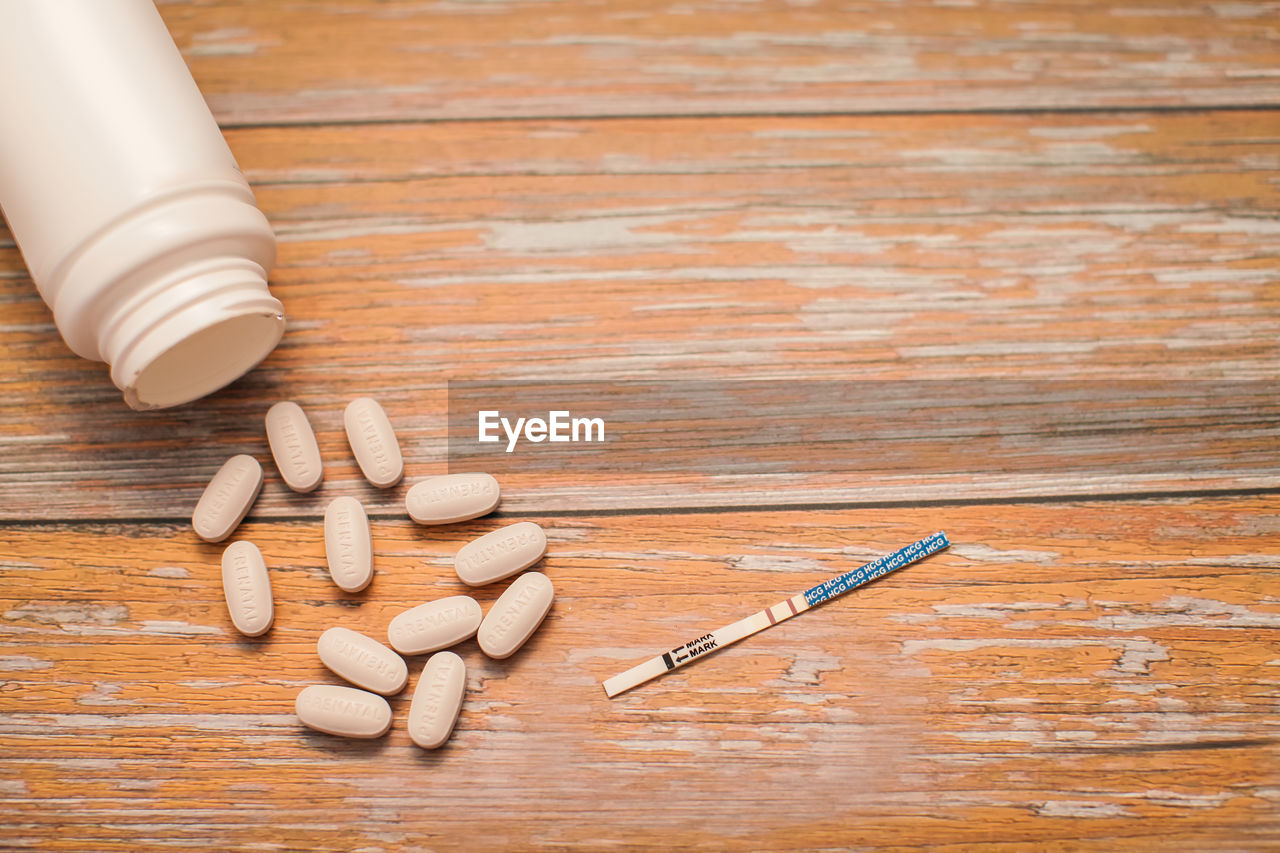 High angle view of pills with pregnancy test and container on table