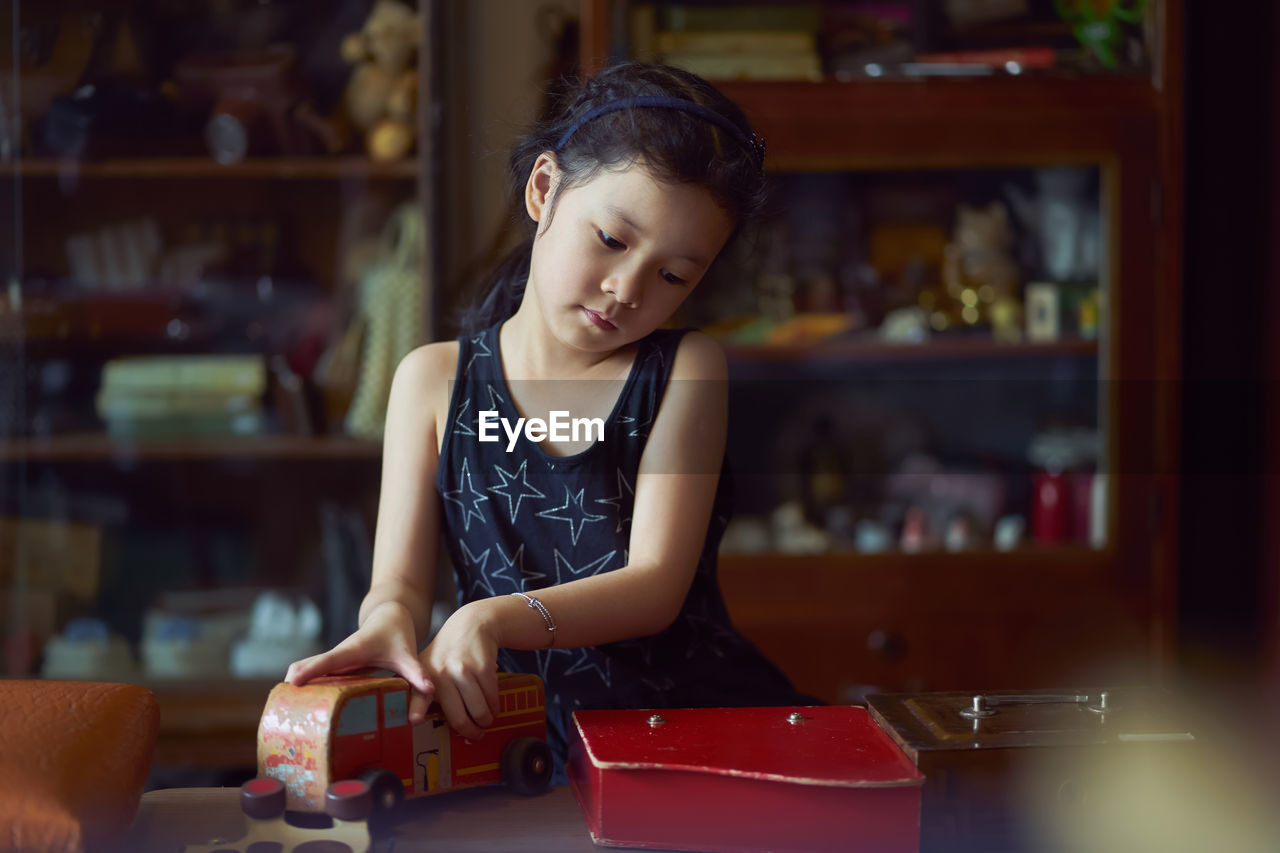 Girl playing toy on table while standing at home