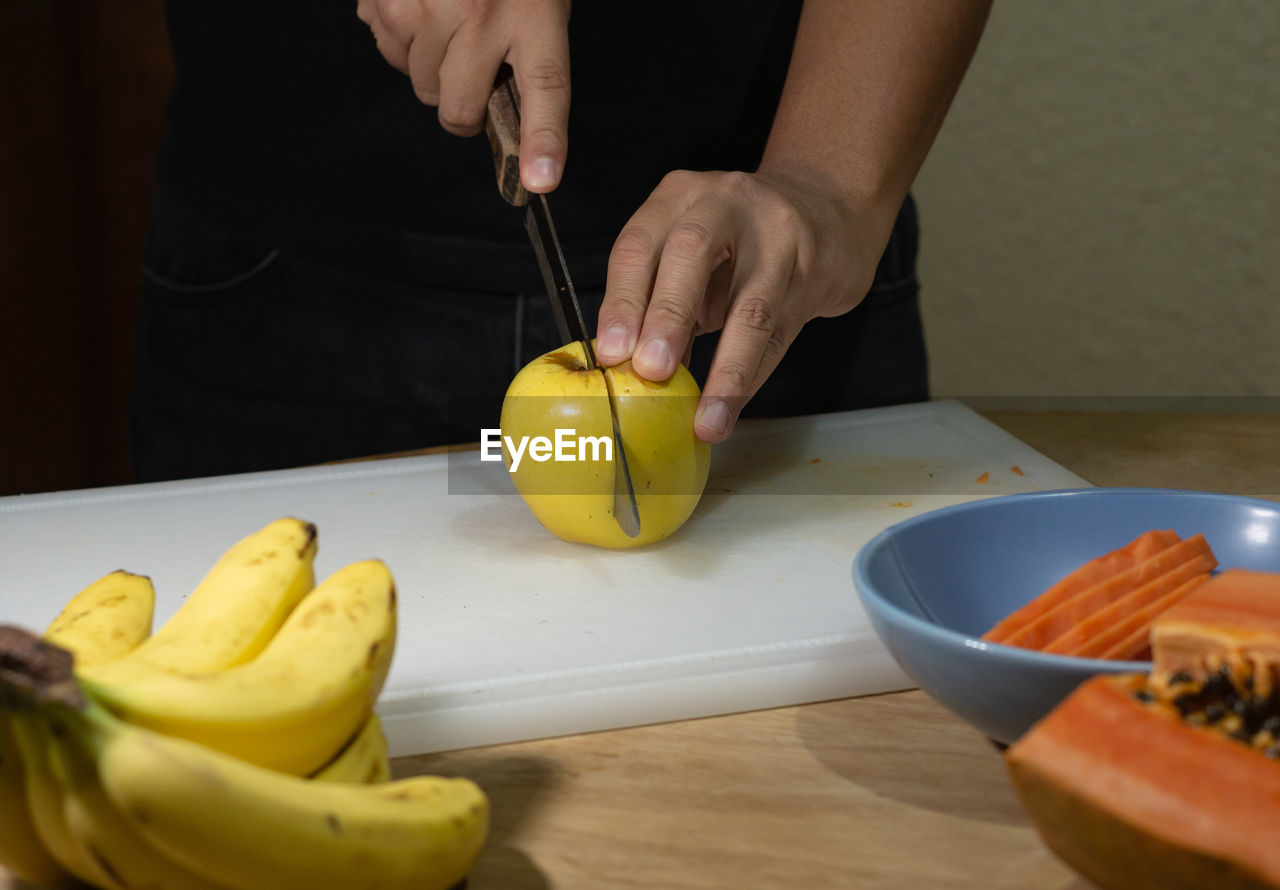 MIDSECTION OF MAN PREPARING FOOD IN KITCHEN