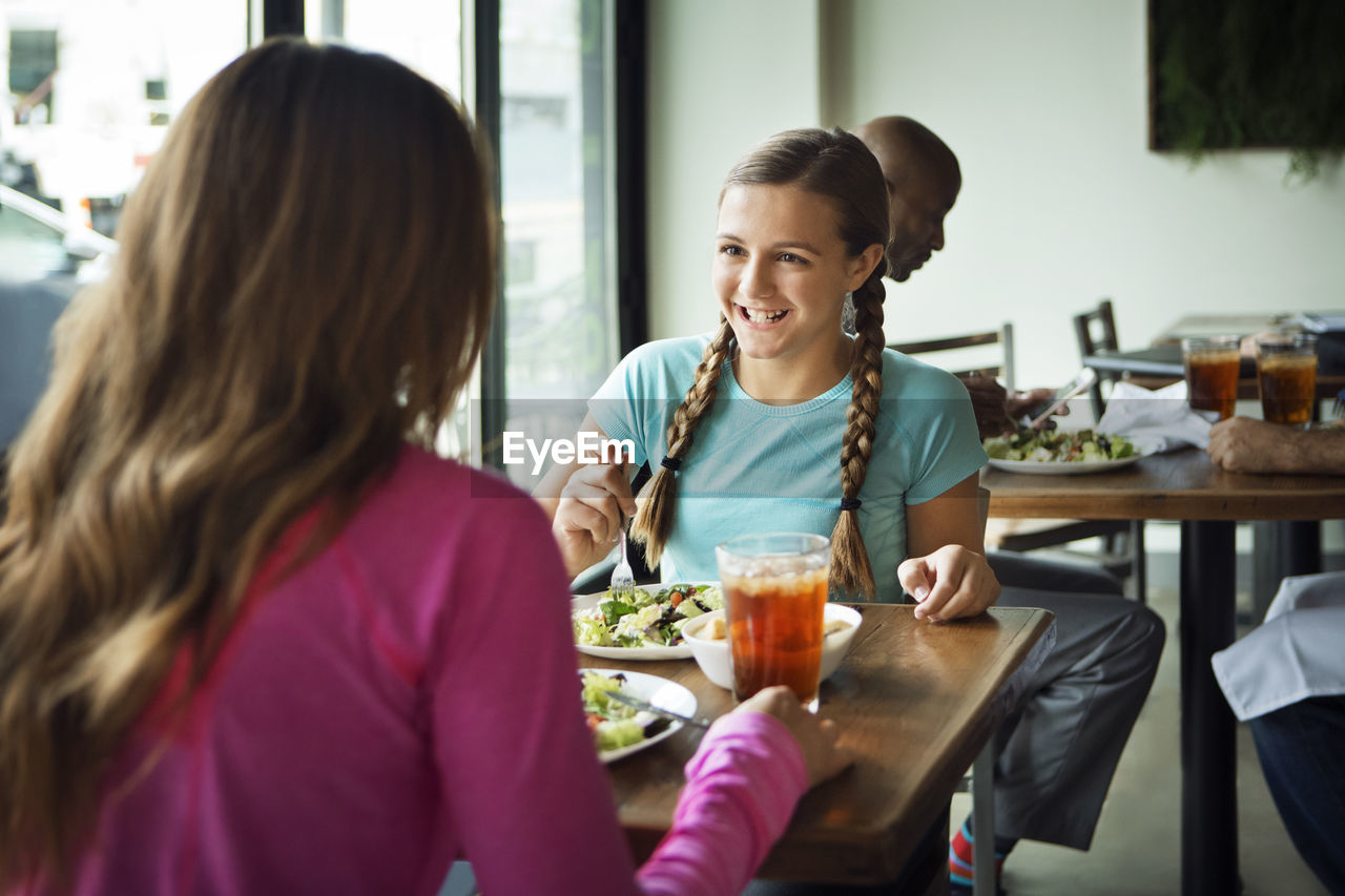 Happy girl looking at mother while sitting in restaurant