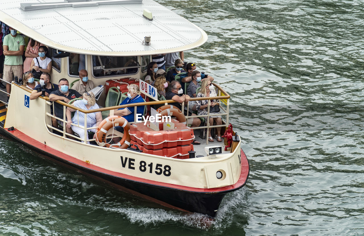 water, nautical vessel, transportation, mode of transportation, group of people, vehicle, boat, men, travel, day, nature, sea, adult, women, watercraft, ship, outdoors, leisure activity, vacation, boating, trip, waterfront, large group of people, holiday, crowd, speedboat, tourism, lifestyles, high angle view, sailing, tourist