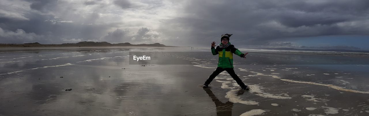 Boy posing at beach against sky