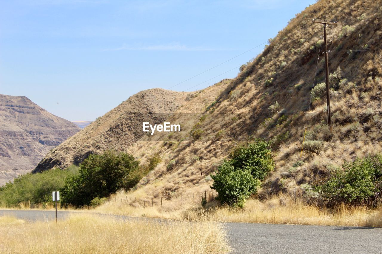 Scenic view of road amidst field against sky