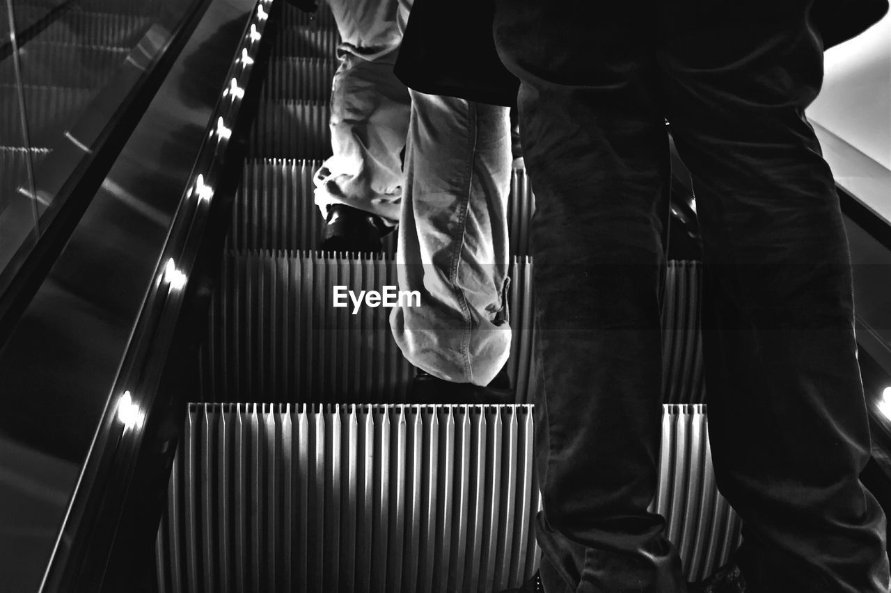 Low section of people standing on escalator