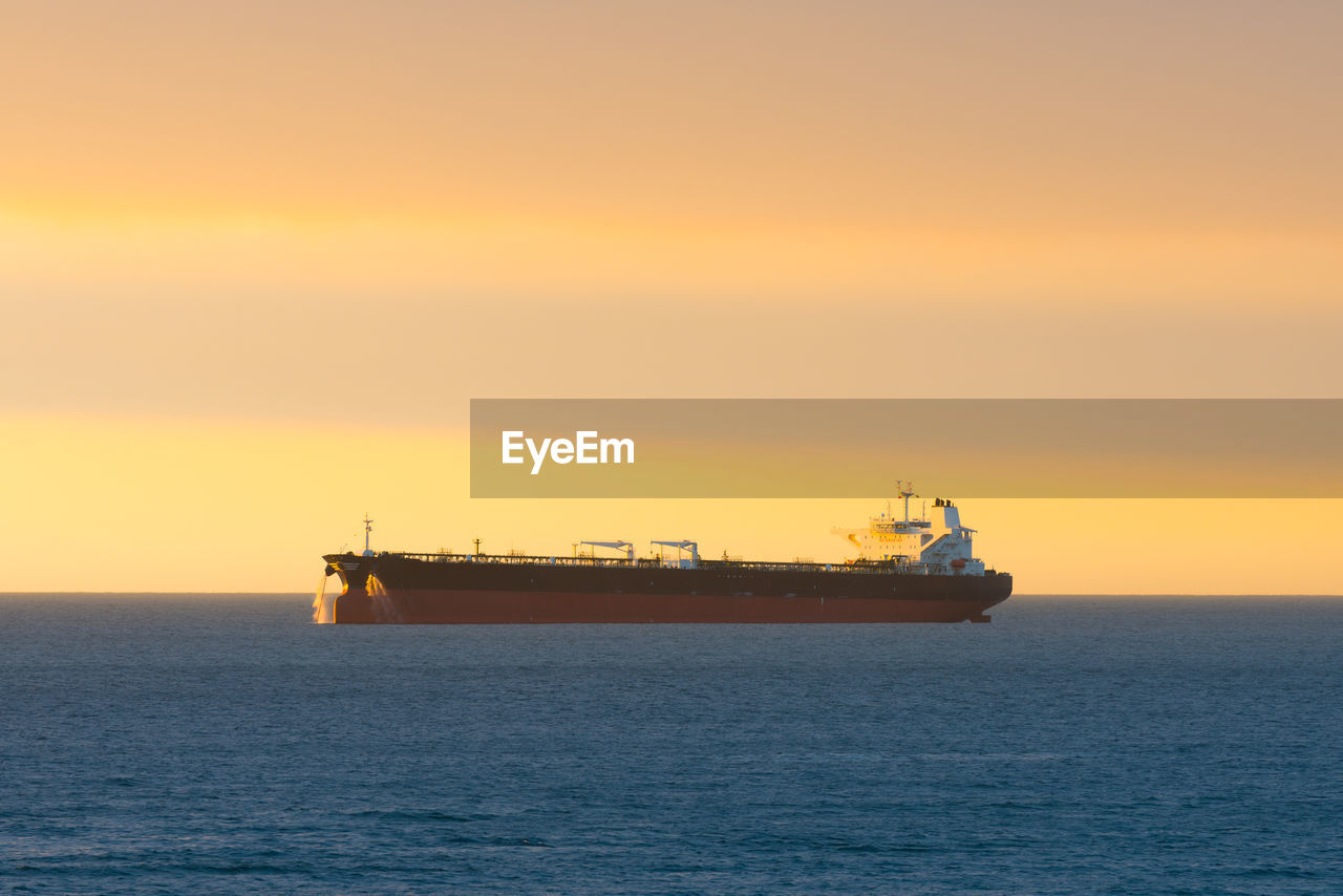 Cargo ship at sunset in the coasts of chile outside the port of valparaiso.