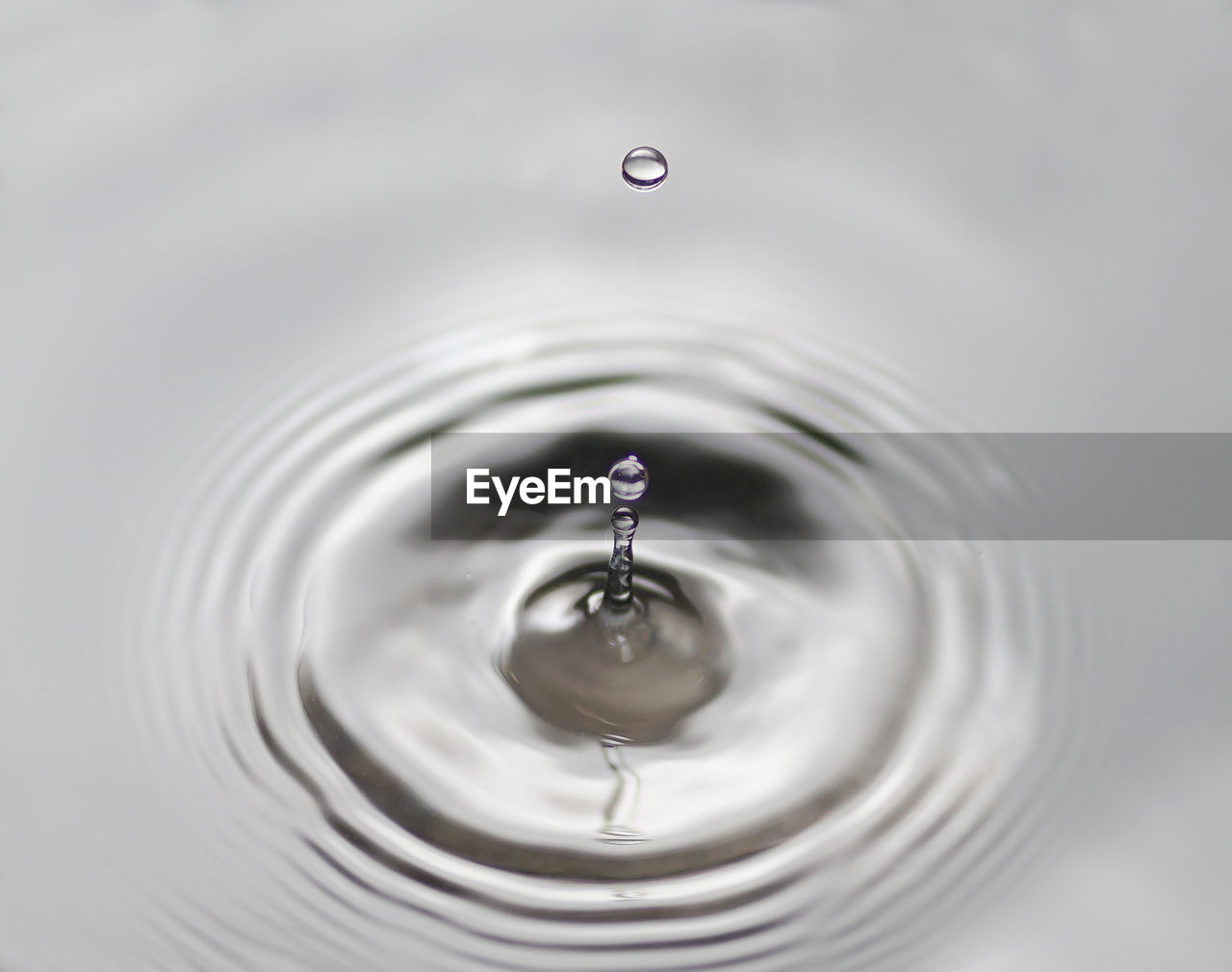 CLOSE-UP OF DROP FALLING ON WATER IN DRINKING GLASS