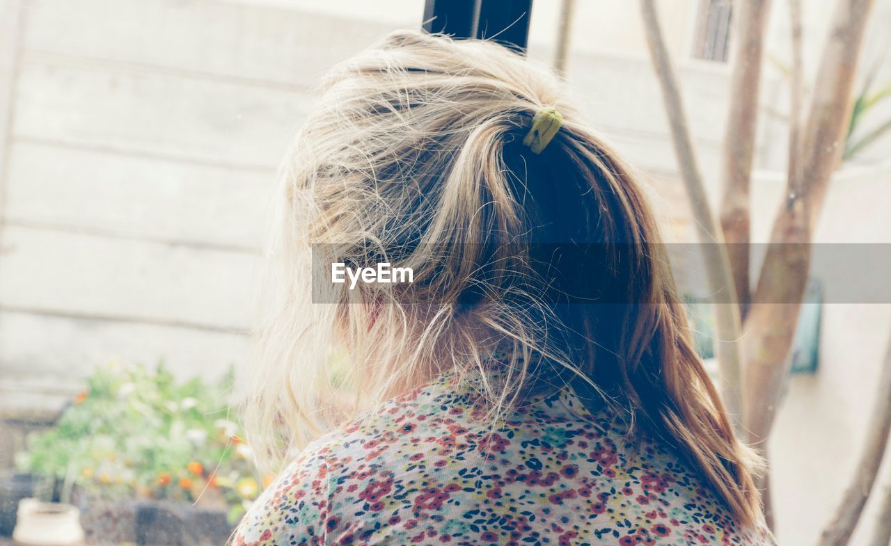 Close-up rear view of girl with messy hair by window at home