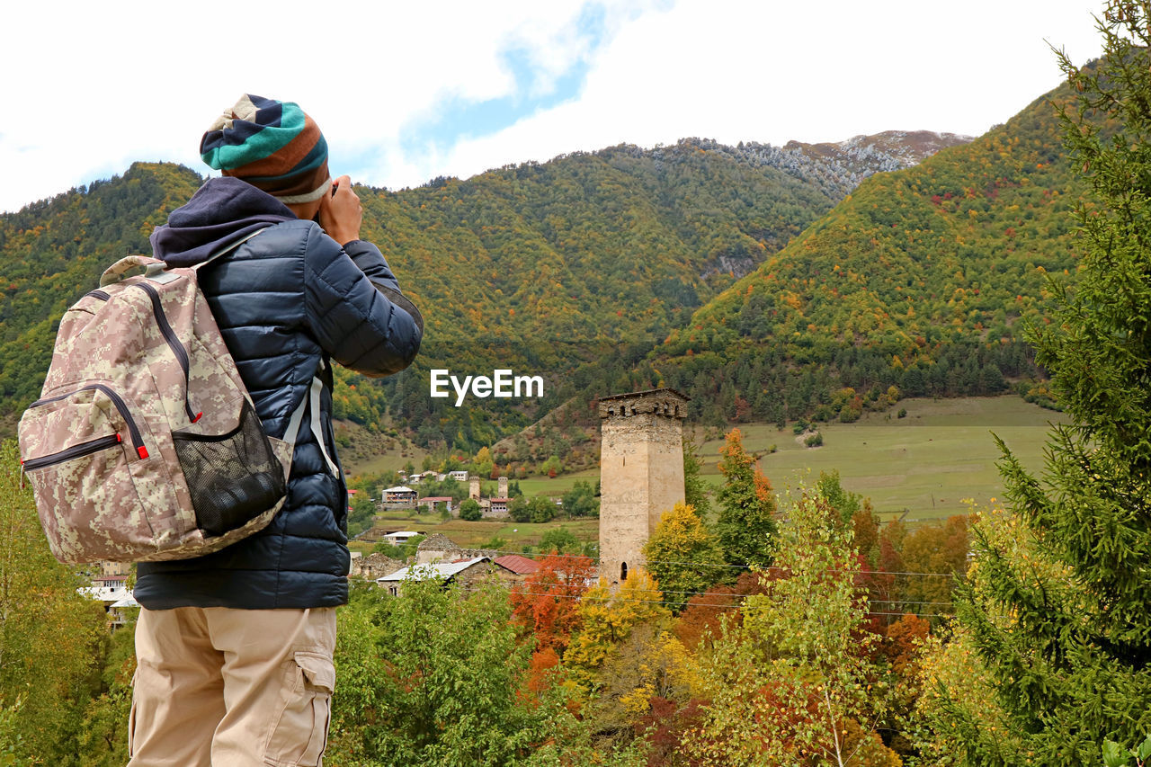 REAR VIEW OF MAN LOOKING AT VIEW OF TREES