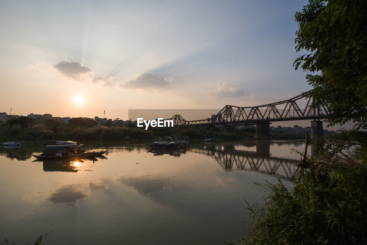 Bridge over river against sky at sunset