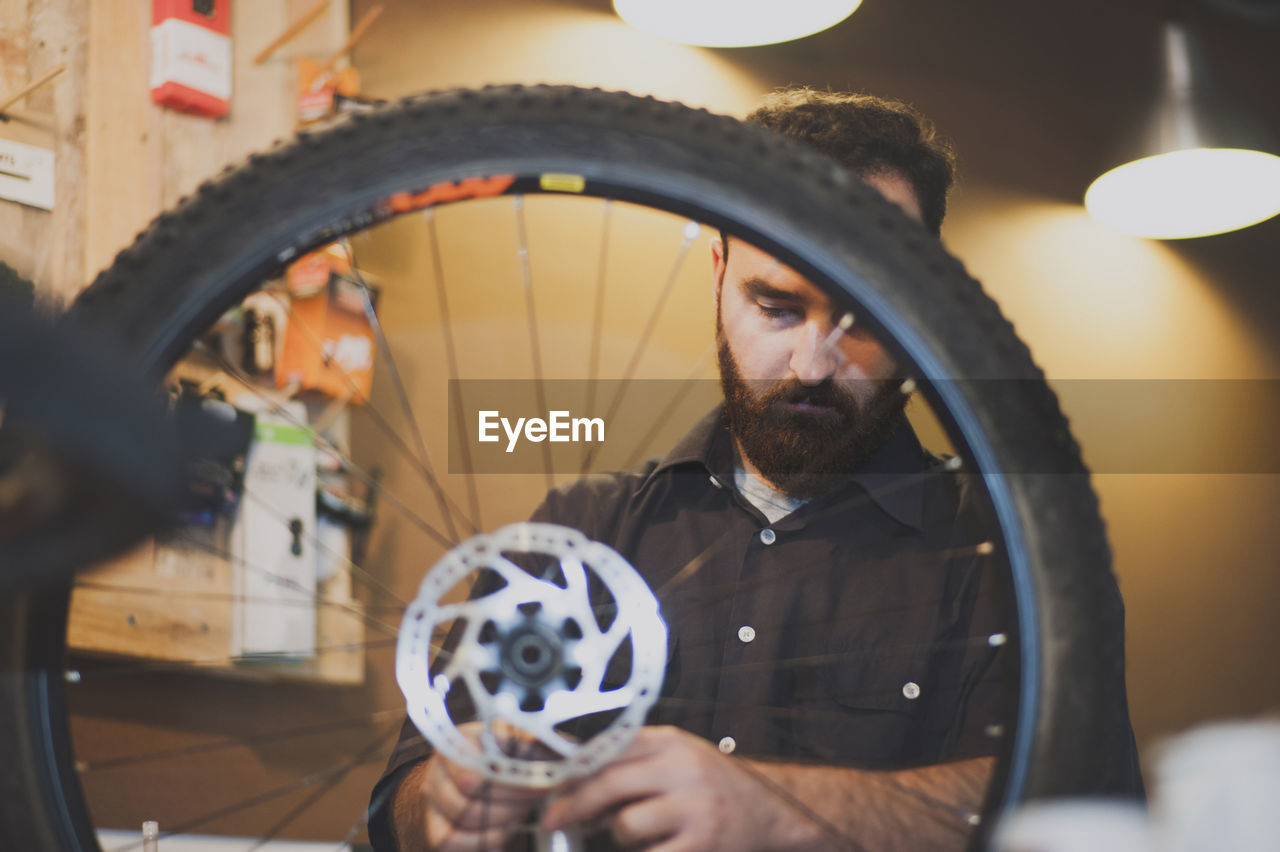 Male mechanic fixing tire at bicycle workshop