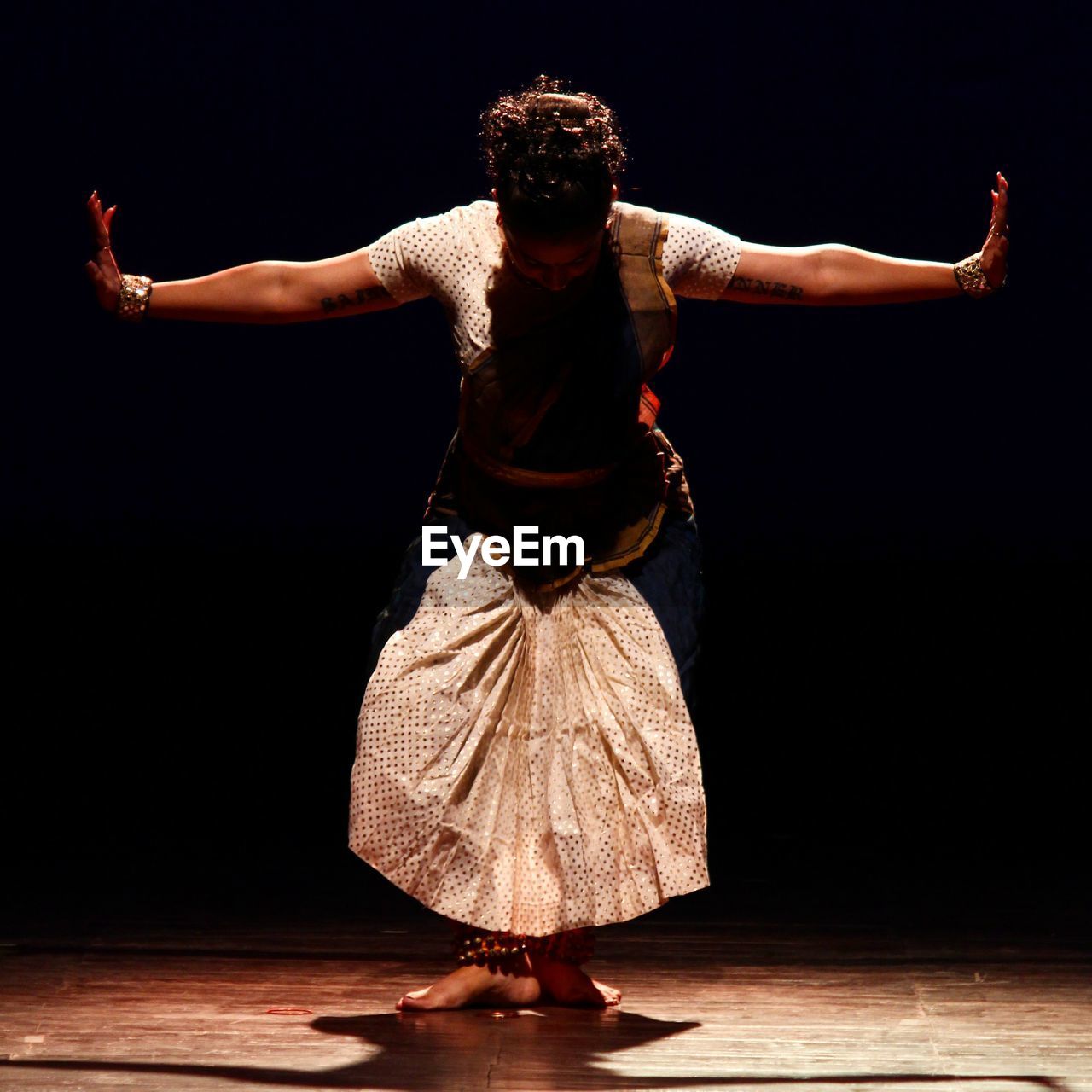 Full length of mid adult woman dancing on stage against black background