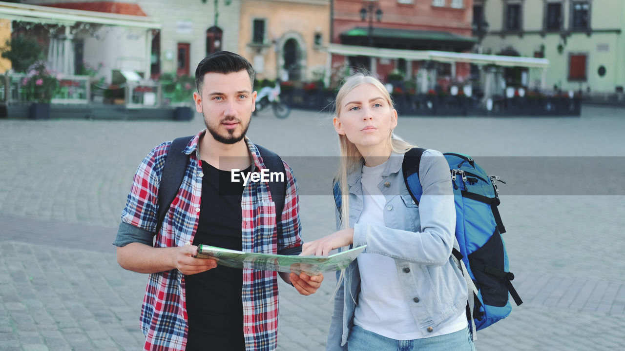 YOUNG COUPLE STANDING ON SIDEWALK