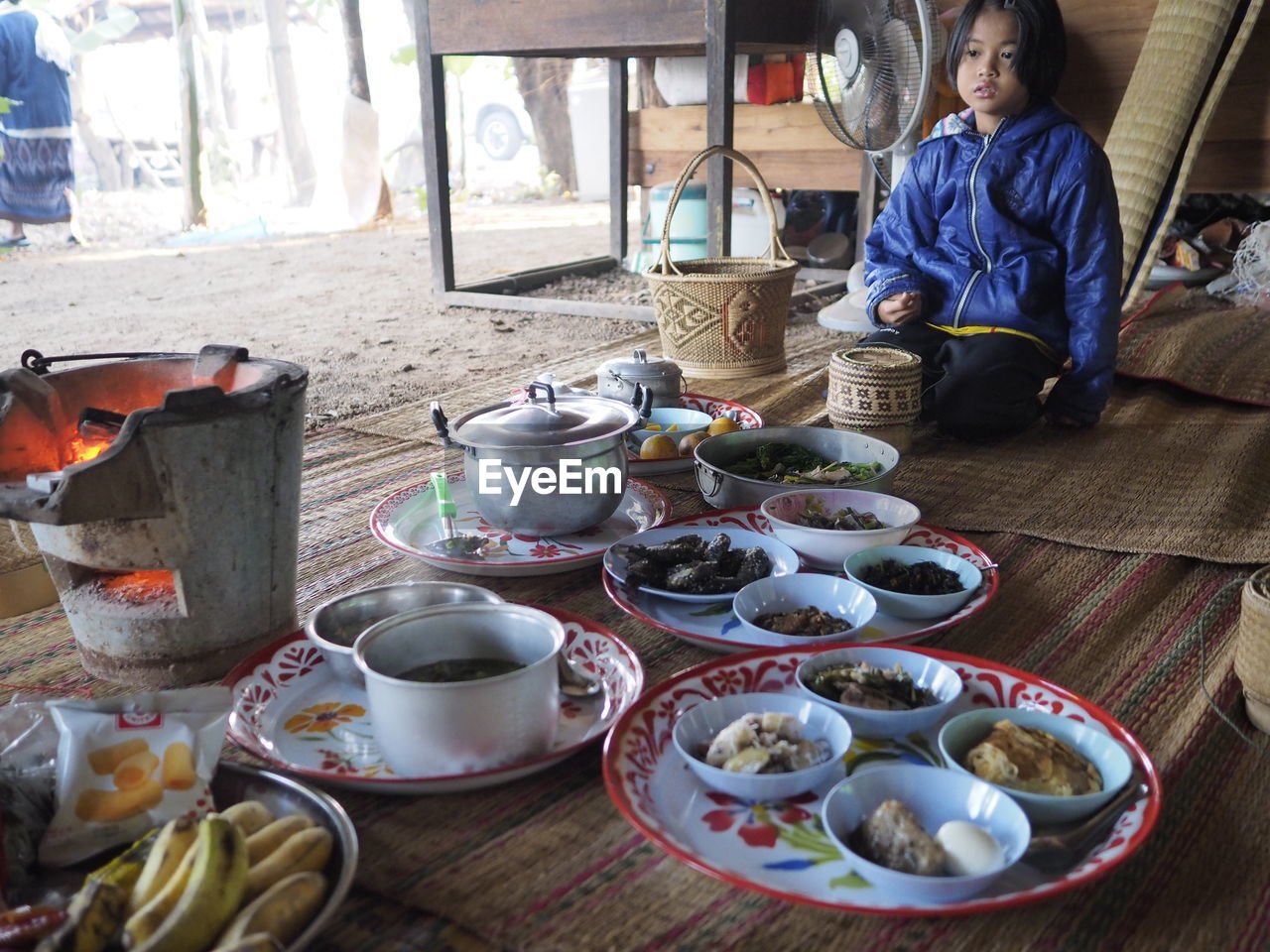 Girl with various food sitting on carpet