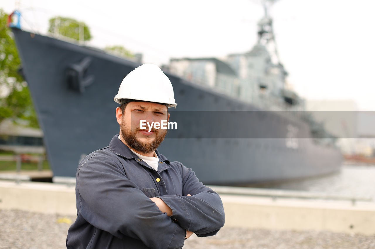 Portrait of sailor standing against ship