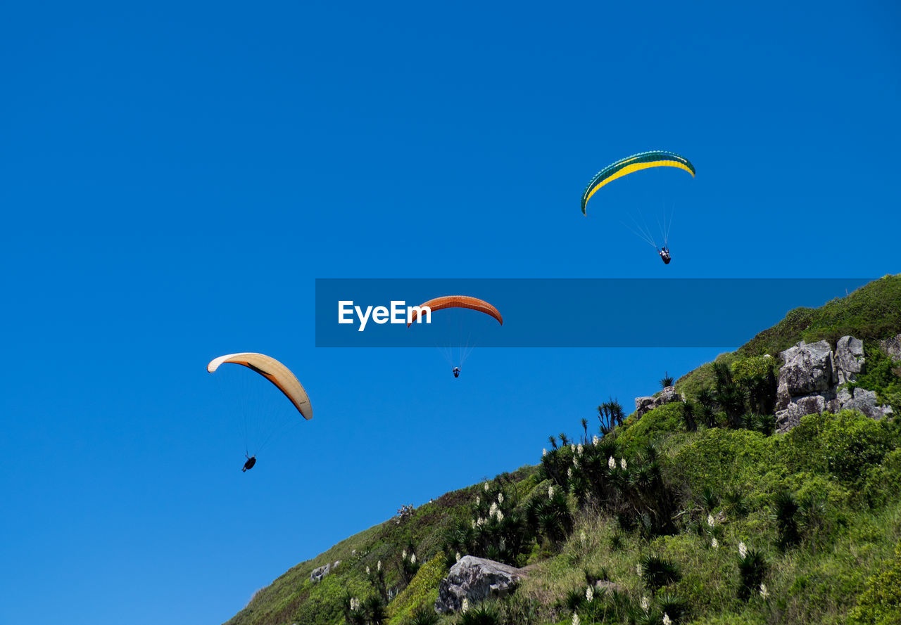 LOW ANGLE VIEW OF PARAGLIDING AGAINST SKY