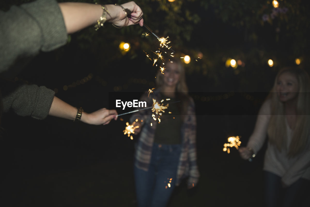 Female friends enjoying with sparklers at night