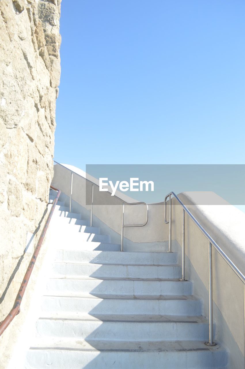 Low angle view of steps leading towards blue sky