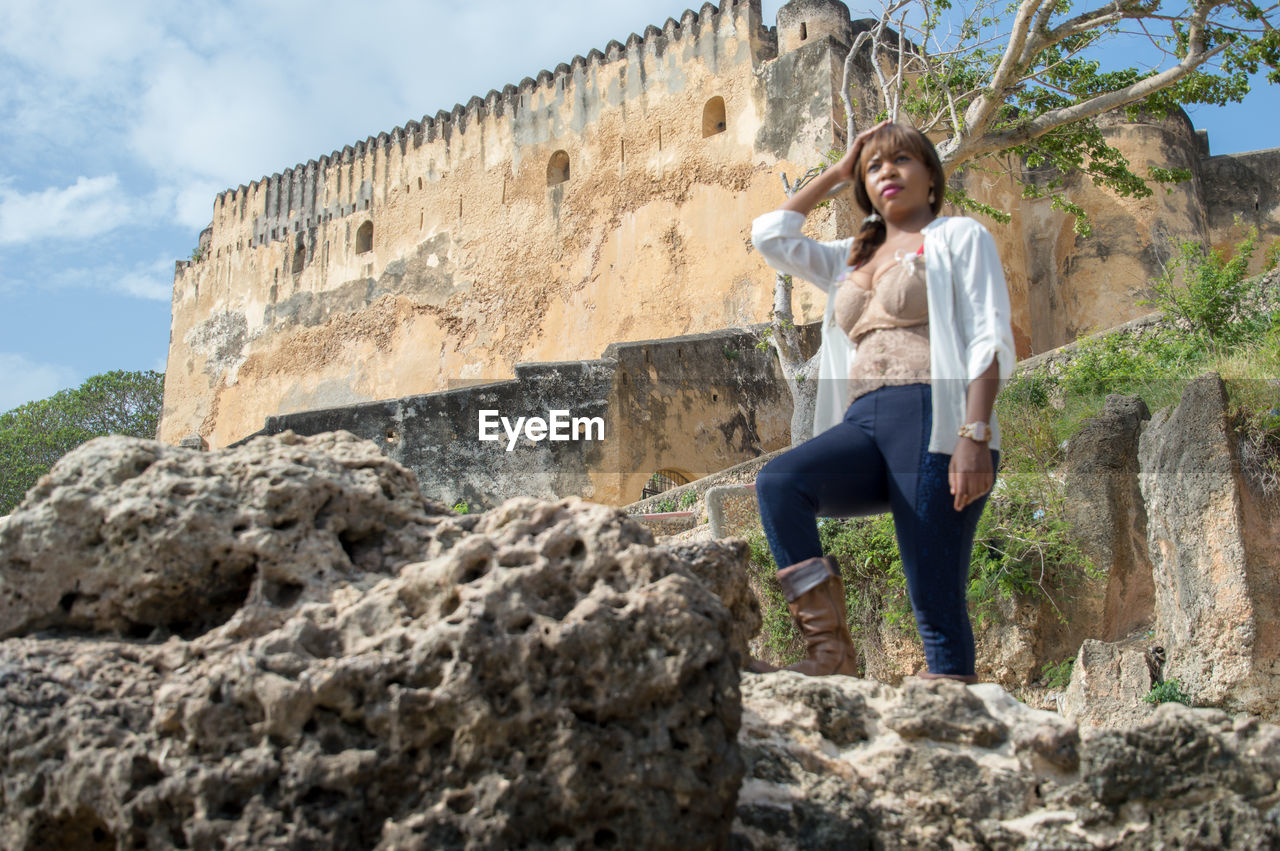 Low angle view of woman standing on rock against fort