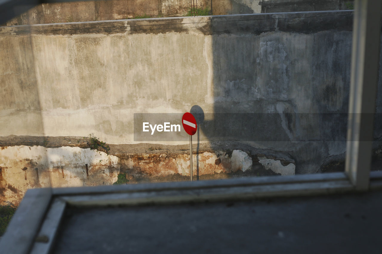 Low angle view of building against wall with stop sign