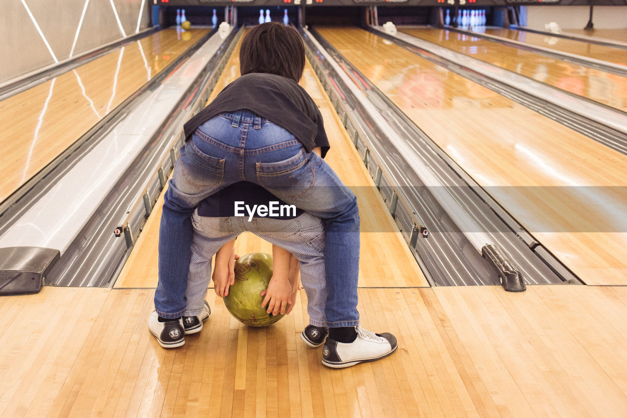 Rear view of siblings with ball in front of bowling alley