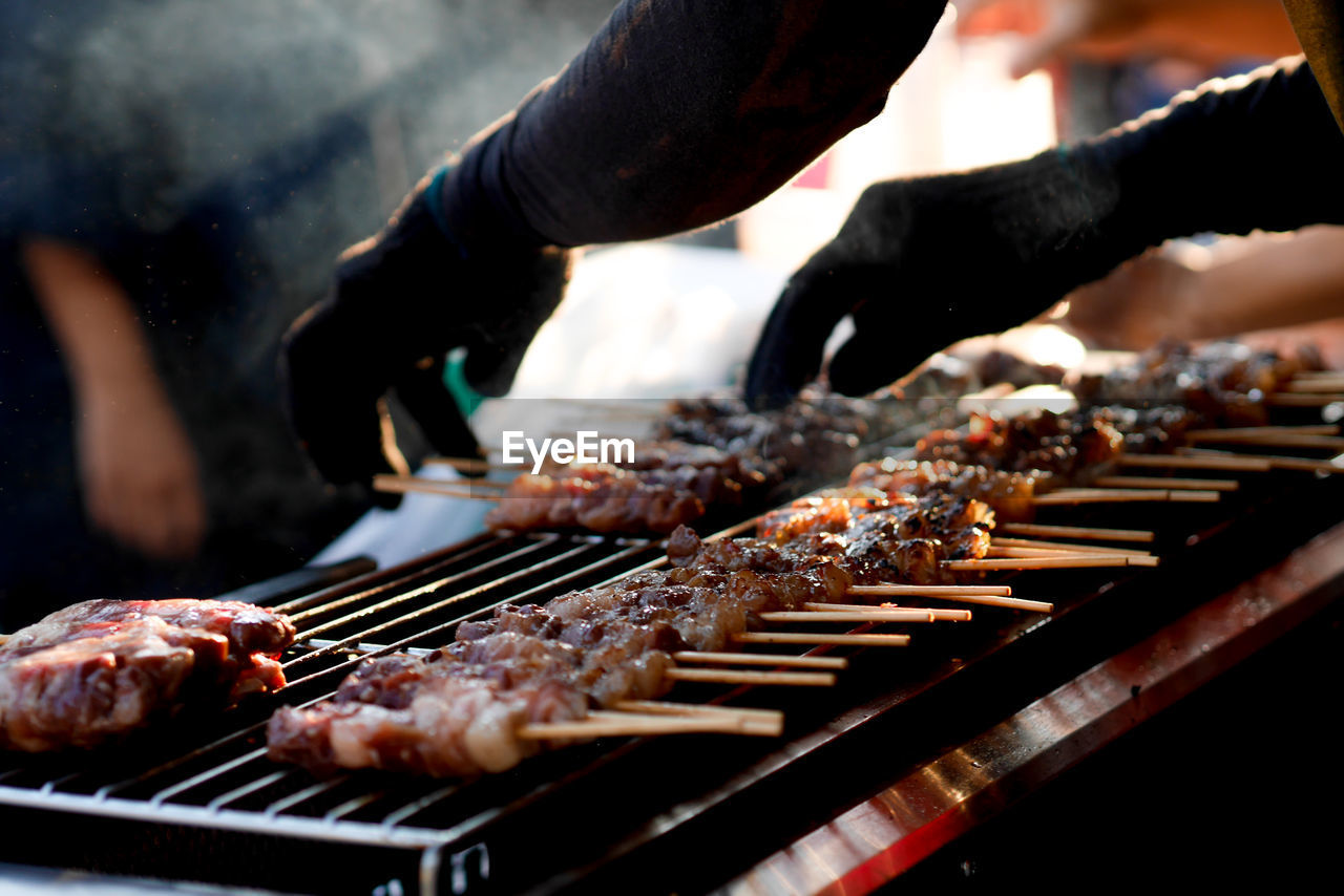 Cropped hands of man cooking food on grill