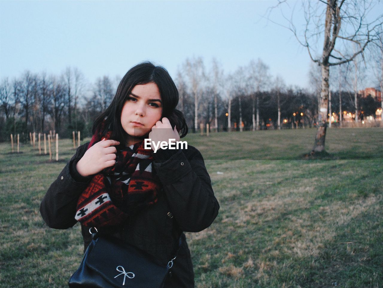 Portrait of young woman standing on land against clear sky