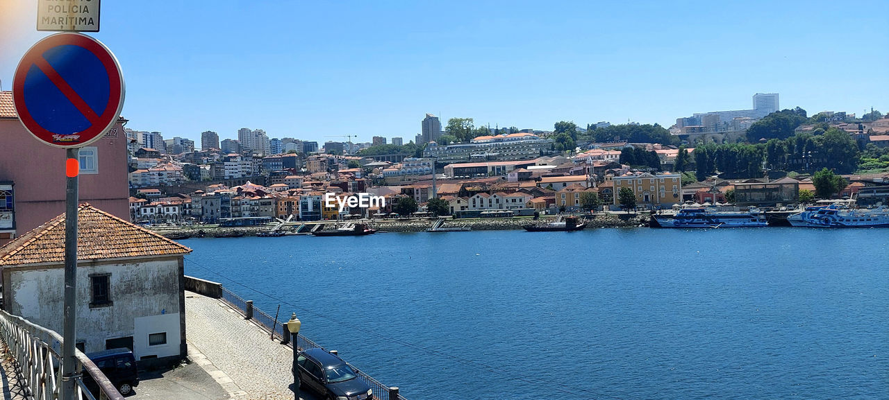 RIVER BY BUILDINGS AGAINST CLEAR BLUE SKY