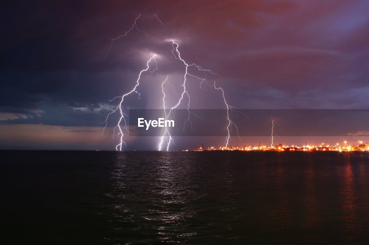 Lightning over sea against cloudy sky