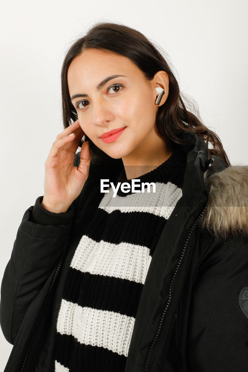 women, adult, portrait, one person, studio shot, waist up, indoors, looking at camera, photo shoot, young adult, outerwear, smiling, white background, female, clothing, long hair, technology, communication, hairstyle, happiness, emotion, telephone, wireless technology, fashion, black, lifestyles, front view, using phone, sleeve, looking, standing, person, brown hair, businesswoman, mobile phone, holding, striped, positive emotion, collar, casual clothing