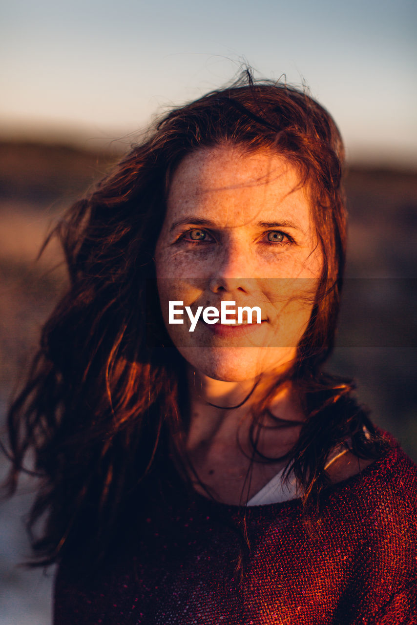 Portrait of beautiful young woman standing against sky during sunset