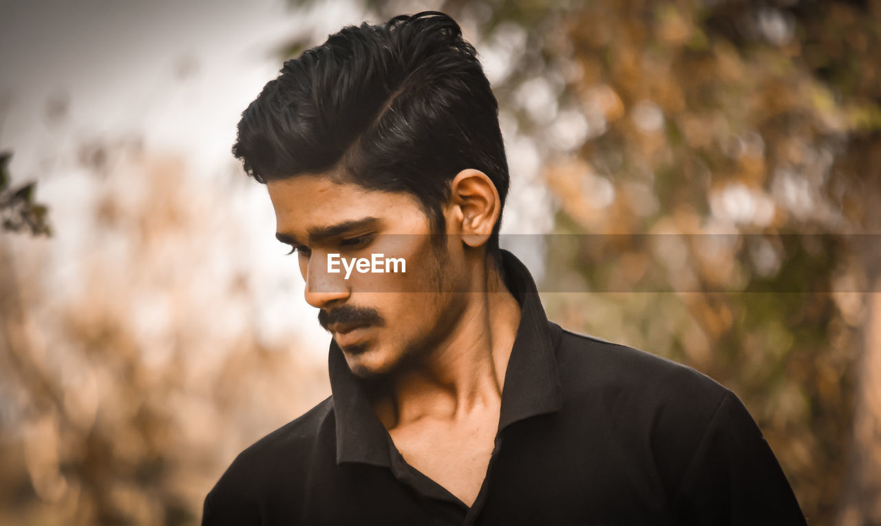 Portrait of young man looking away outdoors