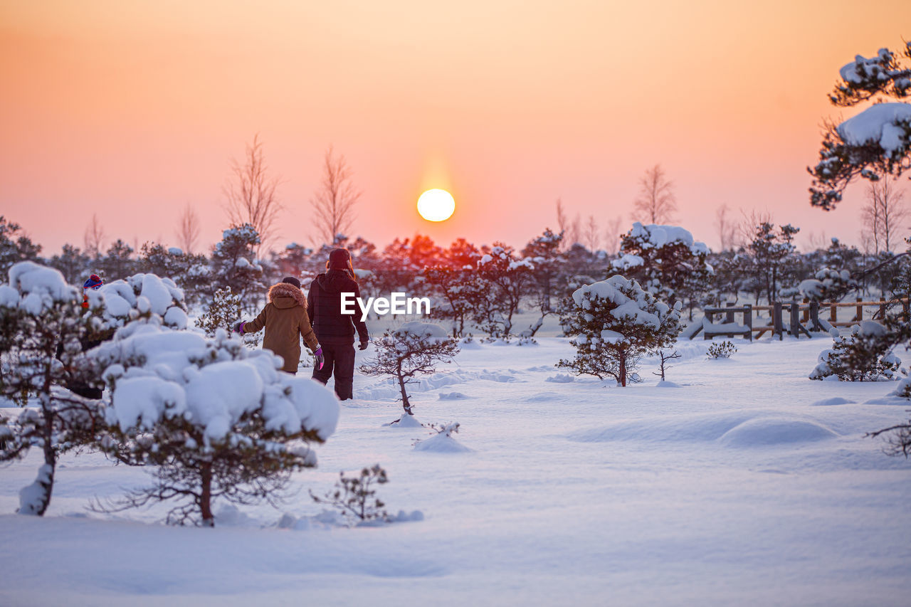 SCENIC VIEW OF SNOW FIELD AGAINST SKY AT SUNSET