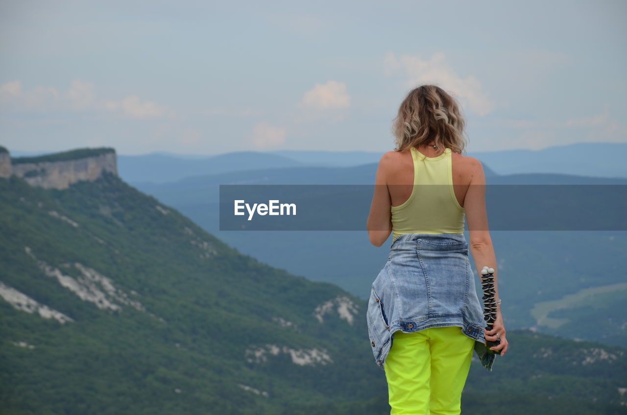 Rear view of woman standing on mountain against sky