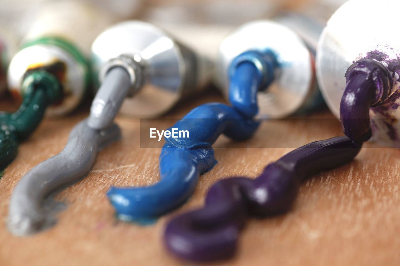 Close-up of colorful paints spilled from tubes on wooden table