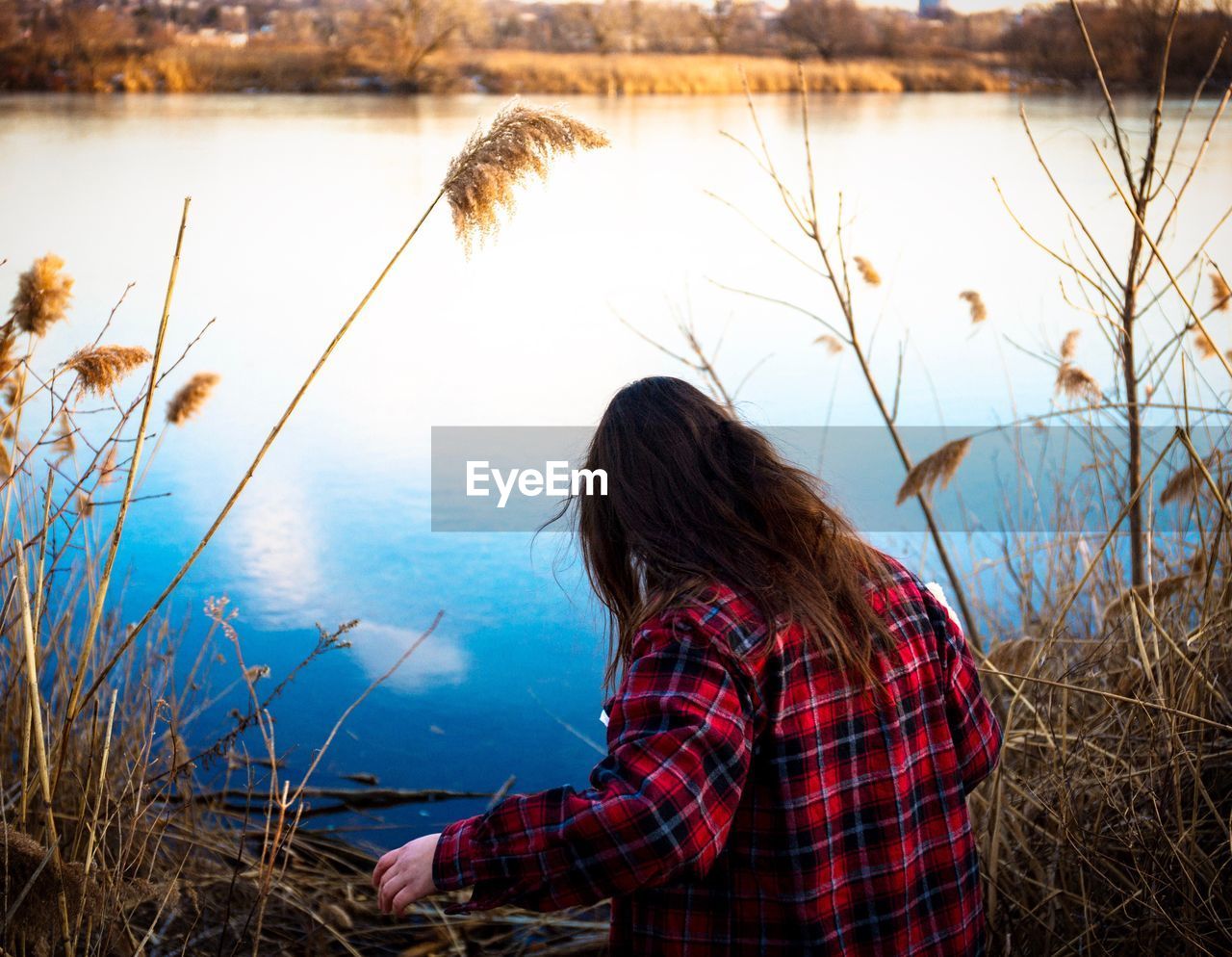 Rear view of woman standing by lake