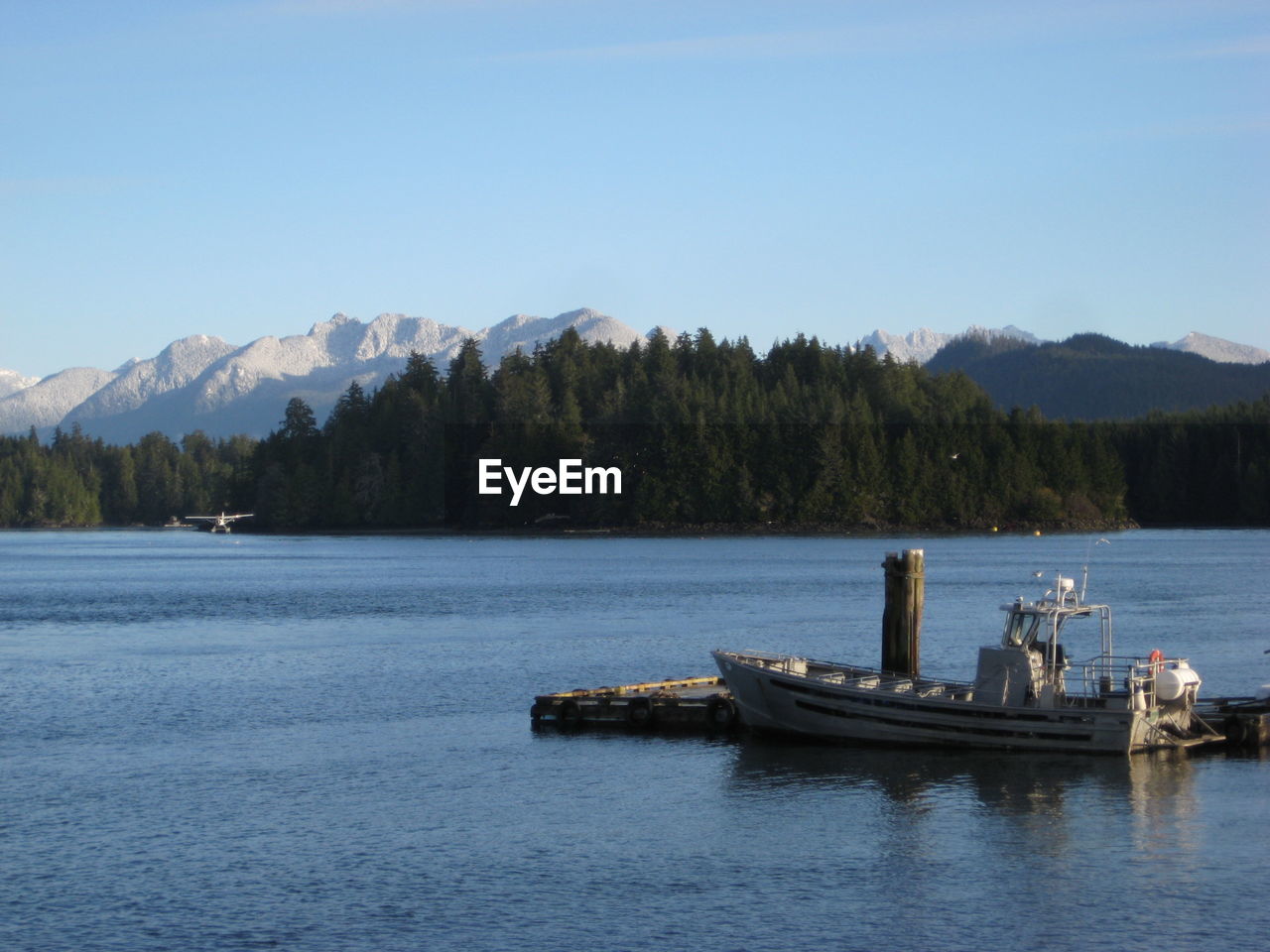 Boat moored by wooden post on lake