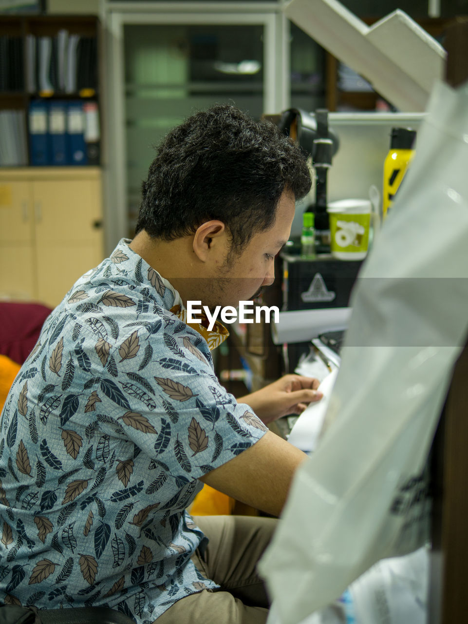 REAR VIEW OF MAN LOOKING AT TABLE