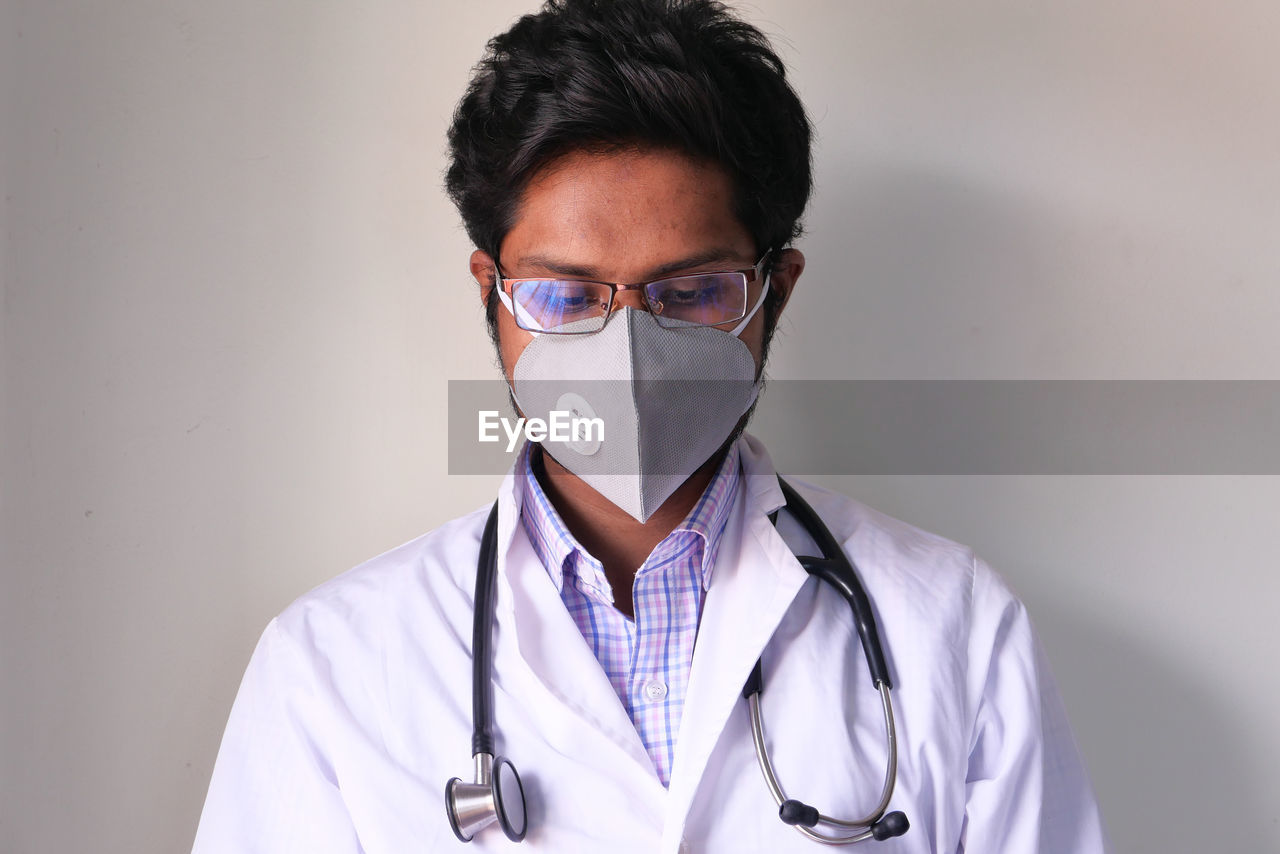 Close-up of doctor wearing mask sitting at office