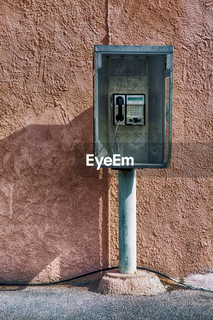 CLOSE-UP OF TELEPHONE POLE AGAINST WALL