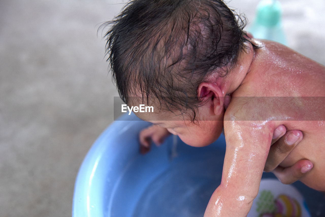 side view of shirtless man washing hands