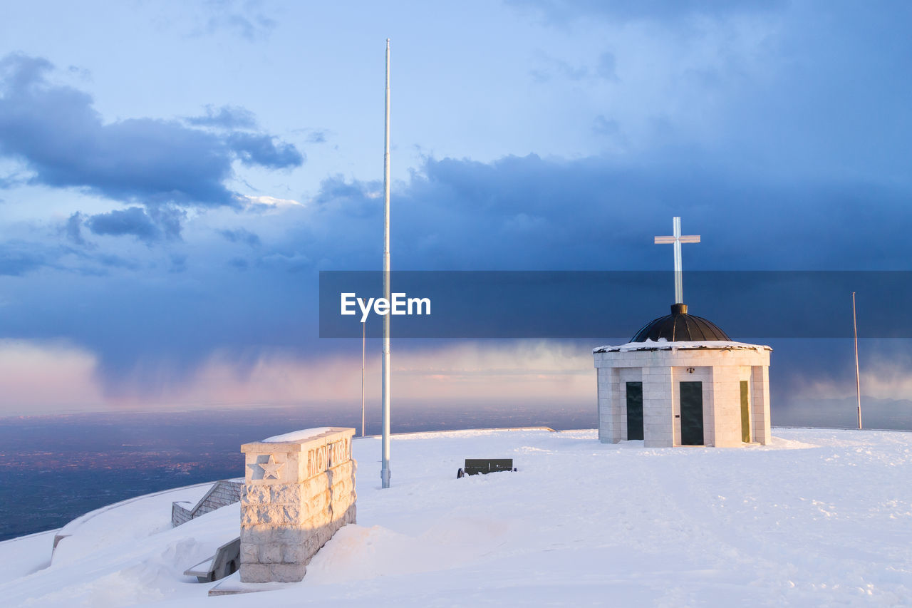 CROSS ON SNOW AGAINST BUILDING