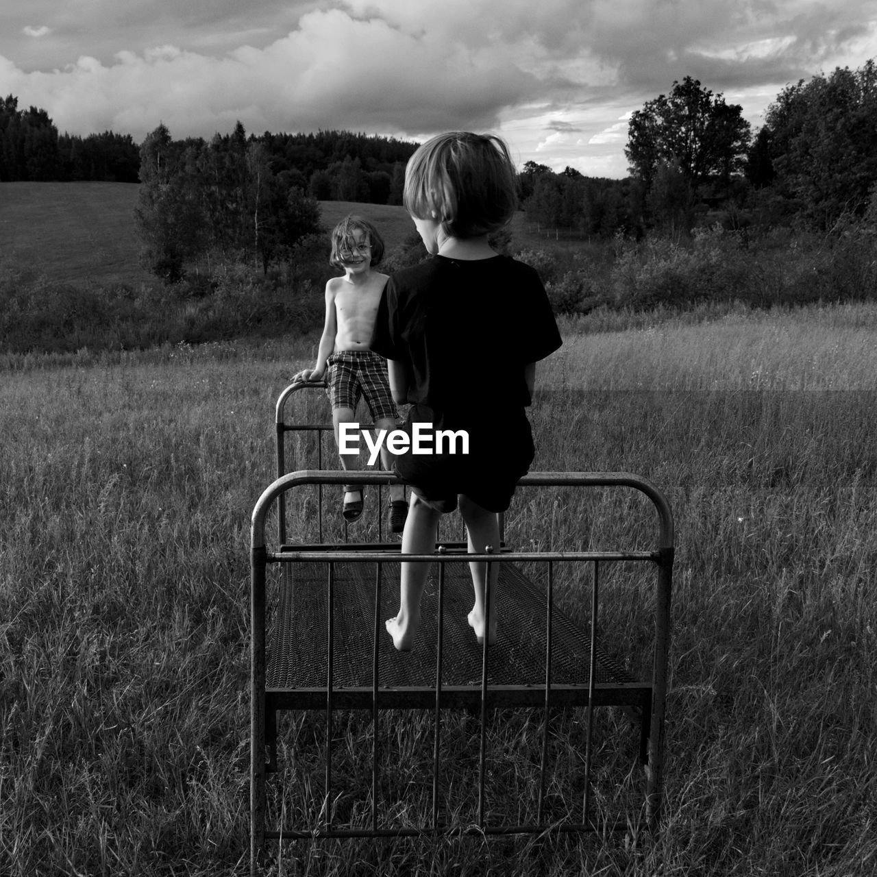 Boys sitting on rusty bed at park