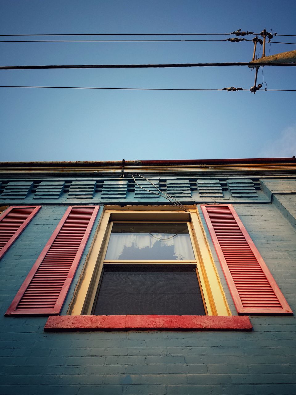 Low angle view of building and power lines against sky