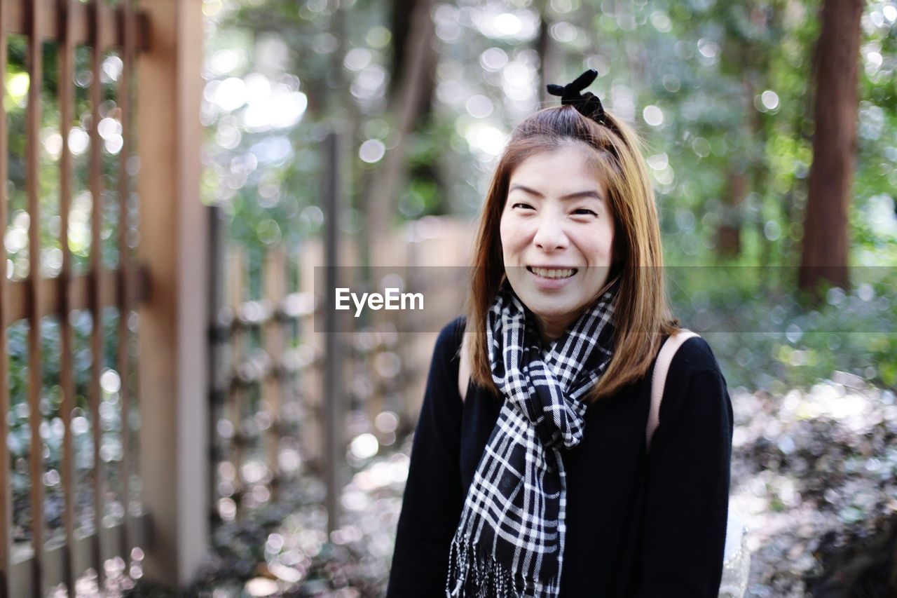 Portrait of smiling mid adult woman standing on footpath