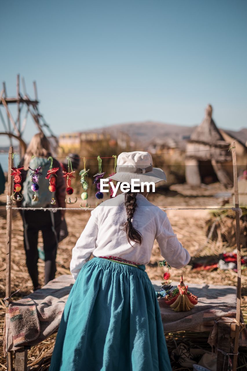 REAR VIEW OF A YOUNG WOMAN AGAINST CLEAR SKY