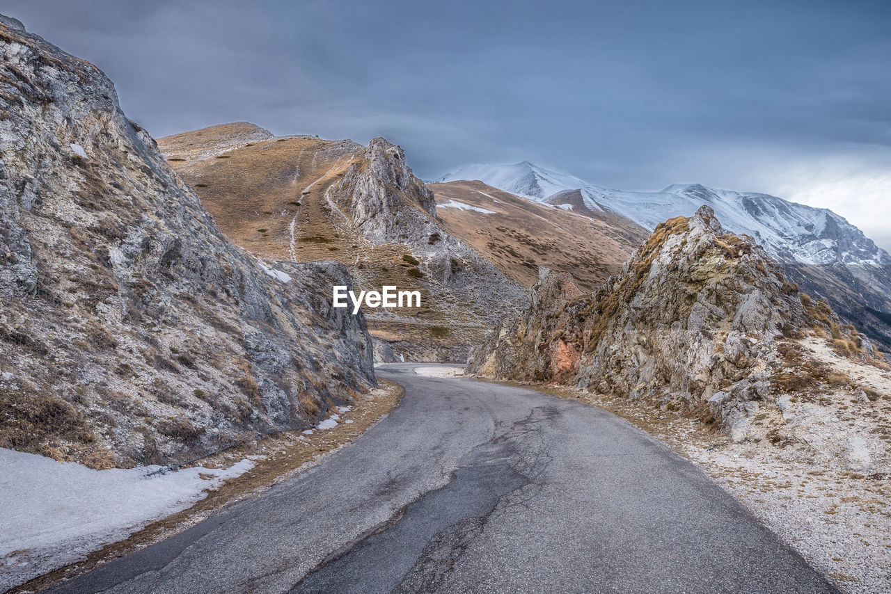 Road amidst snowcapped mountains against sky