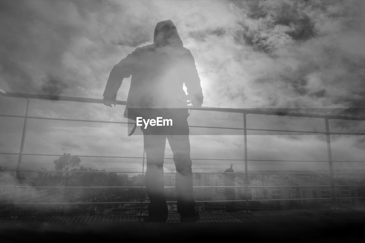 Rear view of man standing on building terrace in foggy weather